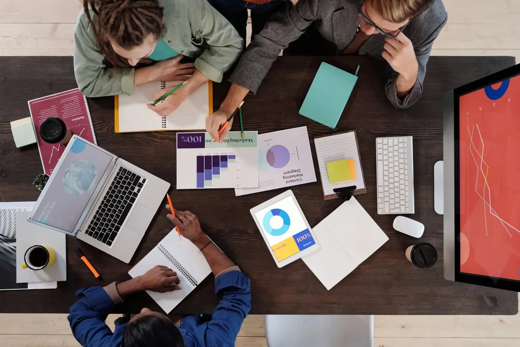 Overhead view of two people sketching ideas beside charts, a laptop and colourful notes
