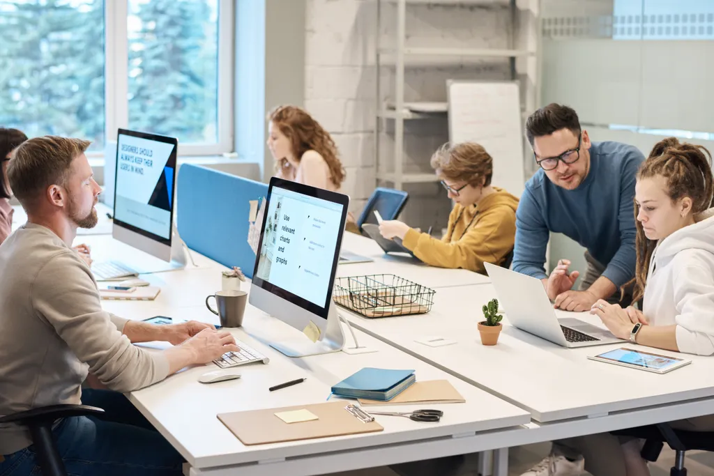 Colleagues working at desks with large monitors in a bright open-plan office