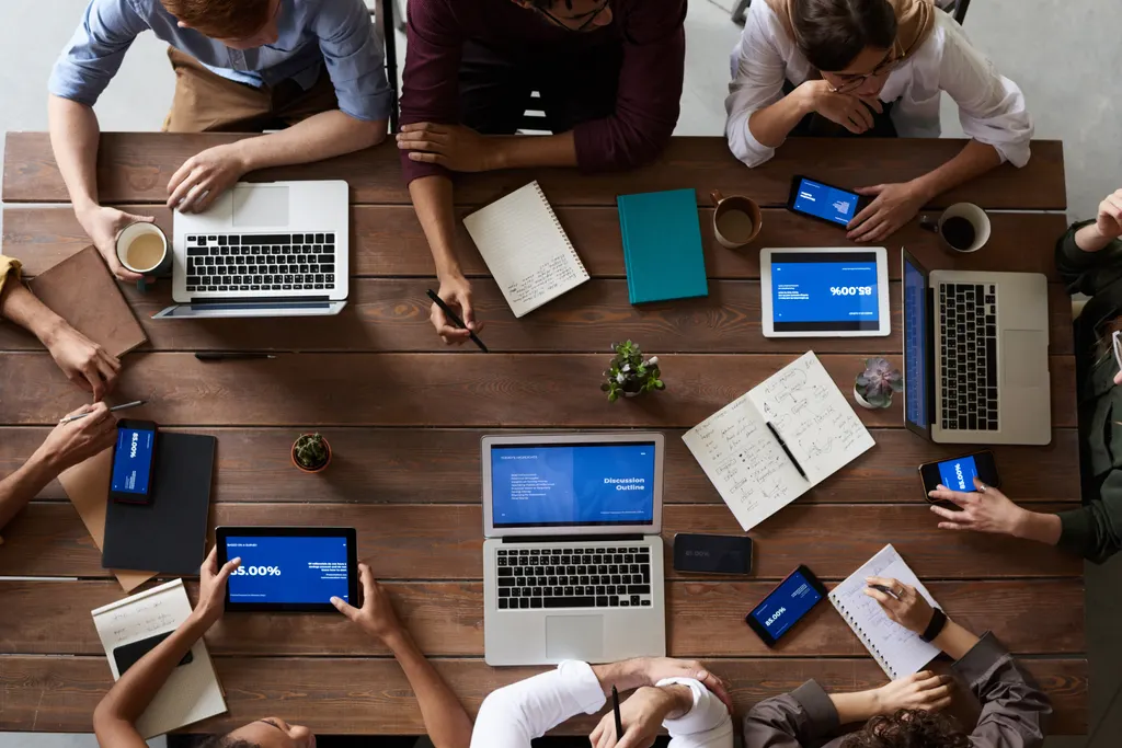 Overhead view of a team working on laptops and tablets showing campaign dashboards